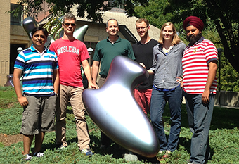 The Lorsch lab standing outdoors around a shiny silver abstract sculpture